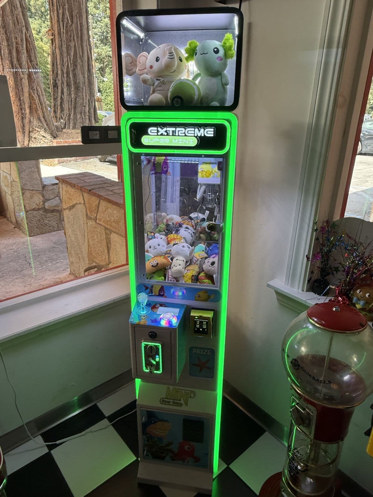 A green-lit claw machine installed in a diner window corner