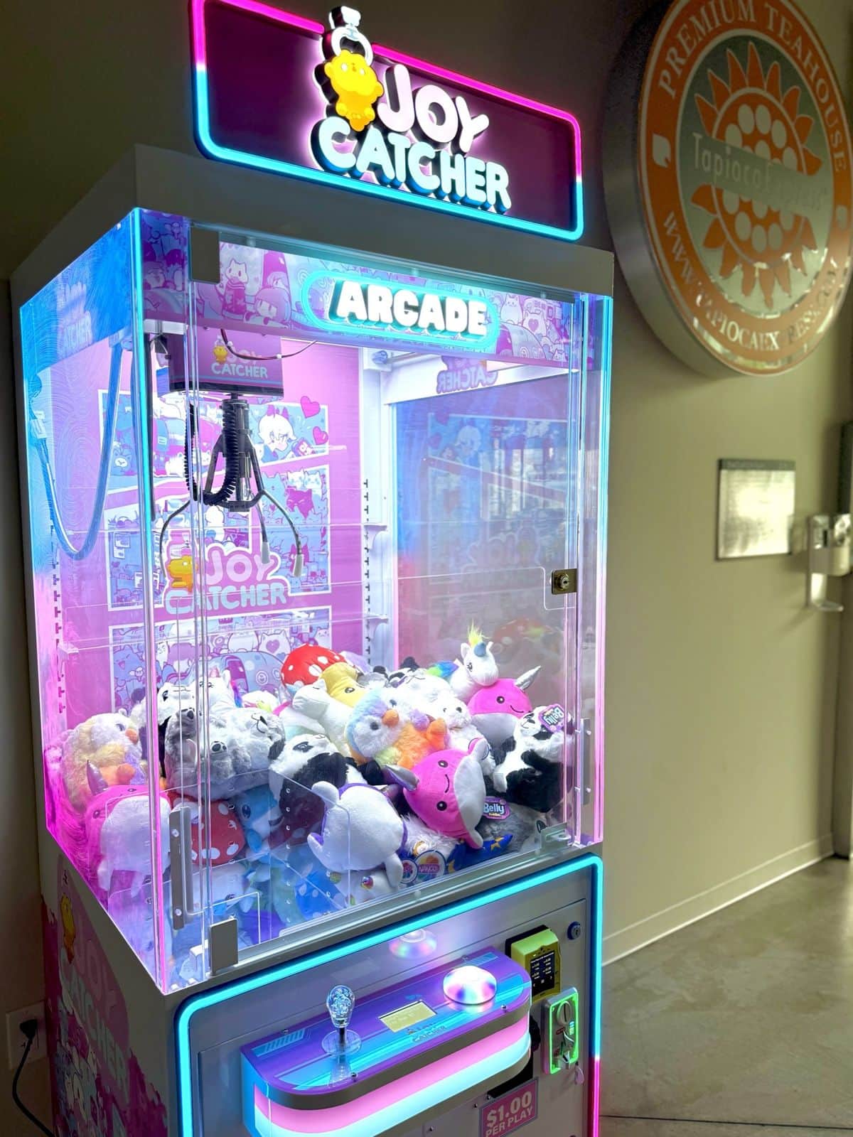 The pink-and-blue lit cabinet of the full-size Joy Catcher, piled with panda and cow plush